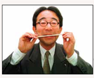 Why Do They Have to Learn to Smile?  In the United States it's very common to see people smiling in public because it's a friendly way to interact socially. In fact, many businesses insist that their salespeople smile at customers because smiling makes the customers feel more comfortable and more likely to buy something. But in Japan, people are very reluctant to show emotions in public and that's become a problem. Japan is currently going through a recession or downturn in business, so there is increased competition to get new customers and keep current customers happy. Said one gas station attendant who is trying to learn to smile more, In this recession, customers are getting choosy about their gas stations, so you have to think positively. Laughter and a smile are representative of this positive thinking (Reitman, 1999, p. A1). But getting salespeople to smile is a radical change in Japan, whose cultural tradition has long emphasized suppressing any public display of emotions, be it happy, sad, or angry. For example, women never smile at their husbands and members of families rarely touch in public and never hug, even when greeting after a long separation. It's still common for women to place a hand over their mouths when they laugh, and men believe that the correct and proper behavior is to show no emotions in public. Unlike American salespeople who often smile and make eye contact with their customers, Japanese salespeople are reserved and greet customers with a simple welcome; smiling, up until now, was totally frowned upon. Because getting salespeople to smile is going against a strong tradition, learning how to smile has grown into a big business in Japan. Employees are now being sent to smile school, which uses various techniques to teach reluctant and bashful students to smile. For example, one technique in learning how to smile is biting on a chopstick (photo above) and then lifting the edges of the mouth higher than the chopstick. Another technique is to follow smile instructions: Relax the muscle under your nose, loosen up your tongue. Put your hands on your stomach and laugh out loud, feeling the 'poisons' escape (Reitman, 1999, p. A1). What is driving all this smiling in Japan is sales and morale. As is well known by American businesses, happy, friendly salespeople are usually the most successful and are great at building company morale. The same is holding true in Japan, where smiley clerks are racking up the most sales and creating a friendly morale. People in other parts of Asia, such as China, also are not accustomed to smiling in social situations. In fact, volunteers for the 2008 Olympics in Beijing were required to take classes on how to smile to ensure that they portray China as hospitable.    Question When having to make money is bucking cultural traditions, what do you think will happen?