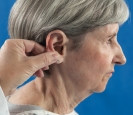   What is the nurse assessing for in the photo? A)  Tenderness B)  Hearing loss C)  Visual deformities D)  Color 