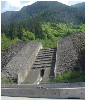 This figure (Figure 13.66) shows one of the mitigation strategies from the Contain the hazard category.It _________________.   A)  collects extra rainwater which cascades safely at the slope base B)  protects from rock slide debris C)  collects and channels debris flow D)  collects wooden debris from a catchment basin