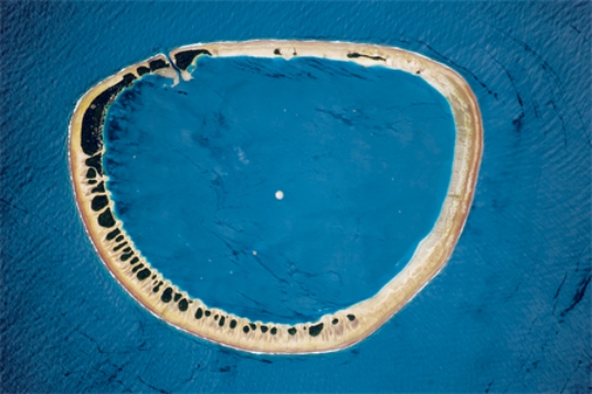 The feature pictured below formed as   A) an island flanked by coral sank. B) mass wasting caused the highest parts of a hill to move downslope until nothing was left in the middle. C) oceanic sea-floor spreading occurred in a circular pattern. D) a recent explosive volcanic eruption left only the sides of the volcano remaining.