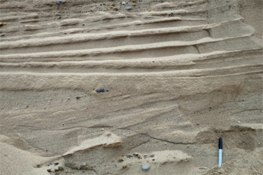 The main reason that the deposits shown here are sorted and stratified is that the glacier that dropped them was   A) moving very slowly. B) accompanied by running meltwater. C) moving through very soft, erodible bedrock. D) moving through very flat terrain.
