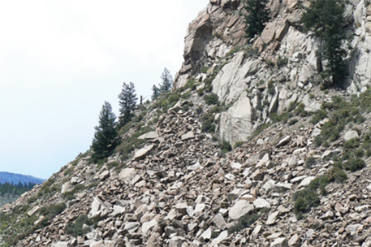 Which of the following surface environments is the most likely site for deposits in this photograph?   A) steep mountain front B) river channel C) sand dunes D) beach E) lake