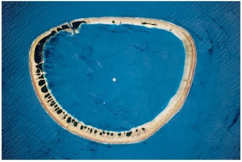 The feature pictured below formed as   A) an island flanked by coral sank. B) mass wasting caused the highest parts of a hill to move downslope until nothing was left in the middle. C) oceanic seafloor spreading occurred in a circular pattern. D) a recent explosive volcanic eruption left only the sides of the volcano remaining.