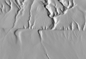 What type of feature is shown in this image?   A)  a fold in metamorphic rocks B)  a scarp along a strike-slip fault C)  erosion of gently tilted layers D)  a hogback