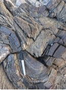 This hard rock contains sand-sized grains of quartz. Fractures cut across, not around the sand grains. What is the correct name for this rock?   A)  schist B)  slate C)  gneiss D)  quartzite