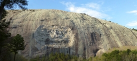 The image shows Stone Mountain in Georgia, a feature made of granite that was uncovered by erosion that removed the overlying and flanking softer rocks. What is the best name for this feature?   A)  An erosional remnant B)  A mesa C)  A thrust fault D)  An anticline