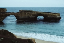 How did the sea cave in this feature form?   A)  erosion of a promontory by waves B)  erosion by blowing beach sand C)  removal of rocks by giant lobsters D)  a rapid drop in sea level