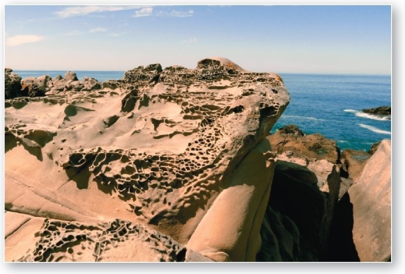 <strong> Tafoni,or honeycomb weathering,in sandstone along the Pacific Coast in Salt Point State Park,California Pitted rock surfaces known as tafoni,or honeycomb weathering,result from weathering.</strong> A)exfoliation B)carbonation C)frost wedging D)salt-crystal growth E)thermal expansion