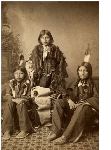 The portraits of Indian students in  The Assimilation of Sioux Students at Carlisle Indian School  illustrate what goal of Indian schools?     A)  To help Indian students maintain ties to their heritage B)  To erase signs of students' Indian heritage C)  To educate Indian students as well as their white counterparts D)  To encourage patriotism to the United States among Indian students