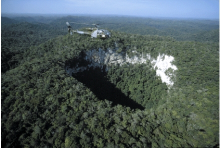 The feature pictured below is formed as a result of subsurface dissolution of limestone rock which can weaken the overlying material and cause it to collapse. These resulting features are called:   A) caves B) sinkholes C) aquifers D) geysers E) artesian wells