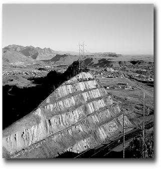 What is the ultimate control of the development of the landscape,the large road cut,in the following picture?   A)  climate B)  human activity C)  time D)  relief