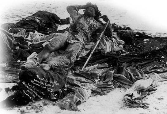   -How did the photographer manipulate the image  The Medicine Man Taken at Wounded Knee, S.D. ? A)  Only the bodies of two Indians were photographed to show that Wounded Knee was not a brutal massacre by white soldiers. B)  A soldier placed the rifle on the medicine man so the photographer could present an image of a hostile Indian. C)  The medicine man's body was laid out in this Christ-like pose to show that he was a noble warrior. D)  The photographer dressed the medicine man in this costume to demonstrate that Indians had not assimilated into American society.
