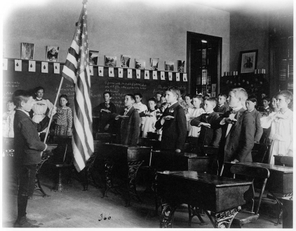   -What was the primary purpose for requiring all students in American schools to recite the Pledge of Allegiance beginning in the 1890s? A)  It honored Columbus on the 400th anniversary of his arrival to the New World. B)  It Americanized the immigrant masses who were coming to the United States at this time. C)  It was part of a campaign to boost public education enrollment. D)  It advanced religious values by making students realize this was  one nation, under God. 