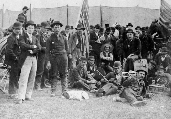   -Why did Coxey's Army choose to pose as they did for this photograph in 1894 as they marched to Washington, D.C., to advocate for a public works project? A)  They wanted the public to know they were members of the middle class calling for reform. B)  They wanted to emphasize their patriotism and not appear to be violent radicals. C)  They wanted to intimidate law officials who threatened them with arrest and violence. D)  They wanted people to recognize them for their military service during the Civil War.