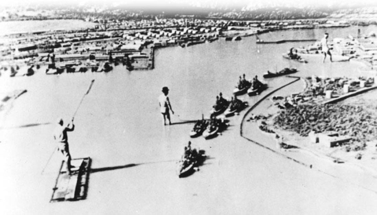   -What major American weakness pictured in this mock-up of Pearl Harbor that was made for a Japanese wartime film led to the Japanese victory at this naval station? A)  The lined-up battleships were easy targets for aerial bombs. B)  The Japanese did not believe that the United States would unite in war against them. C)  America's two aircraft carriers were destroyed in this attack. D)  A Japanese air strike destroyed storage tanks containing millions of gallons of fuel oil.