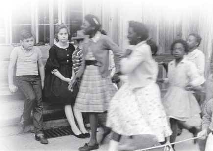 <strong> What does this photograph of children visiting town demonstrate about racial customs in the South?</strong> A) Black children enjoyed town, but white children did not. B) White children were taught to be unsmiling and quiet. C) White children generally preferred to be at home. D) Whites and blacks kept apart even from a young age.