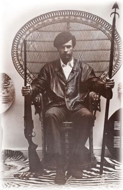 <strong> Why did Black Panther Huey Newton choose to stage this 1967 photograph in this manner?</strong> A) He wanted to convey a militant ideology with symbols of a racial identity rooted in African culture to the public. B) He was an avid hunter of big game in Africa, which symbolized power to the Black Panther Movement. C) He wanted to urge young black men to adopt commando-style clothing that included leather jackets, black pants, black berets, and dark sunglasses. D) He believed this style of dress and the weapons he was holding would intimidate urban gangs in black neighborhoods.