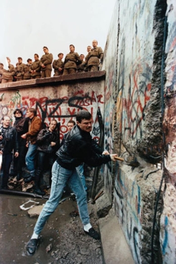   -What does this photograph of one man using a hammer to destroy parts of the Berlin Wall in 1989 symbolize? A)  the frustration shown toward Soviet Premier Mikhail Gorbachev B)  the reaction toward the possible retaliation by East German soldiers standing on the wall C)  the ability of common people to make history and overcome tyranny D)  the anger and resentment that West Germans had toward their countrymen in East Germany