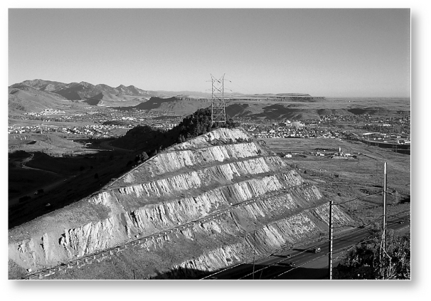 What is the ultimate cause for the development of the landscape,the large road cut,in the following picture?   A)  climate B)  human activity C)  time D)  relief