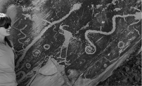 The petroglyph in the image below is carved into _______,revealing the lighter-colored bedrock underneath.   A)  basalt B)  desert varnish C)  caliche D)  salt