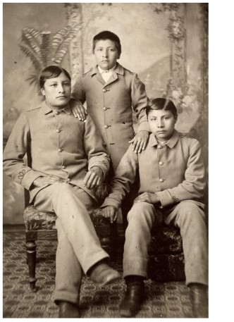 The portraits of Indian students in  The Assimilation of Sioux Students at Carlisle Indian School  illustrate what goal of Indian schools?     A)  To help Indian students maintain ties to their heritage B)  To erase signs of students' Indian heritage C)  To educate Indian students as well as their white counterparts D)  To encourage patriotism to the United States among Indian students