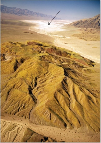   What desert feature is visible in this image, indicated by an arrow? A) Playa lake B) Desert varnish C) Sand dunes D) Inselberg