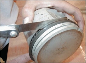 <strong>What is the technician doing in this photograph?  </strong> A)Measuring back clearance B)Measuring side clearance C)Cleaning the rings D)Measuring end gap <div style=padding-top: 35px> 