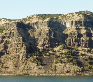 118) What type of rock likely composes the landscape shown in this photograph from the Investigation?   A) metamorphic rocks B) sedimentary rocks C) granite D) volcanic rocks, probably basalt