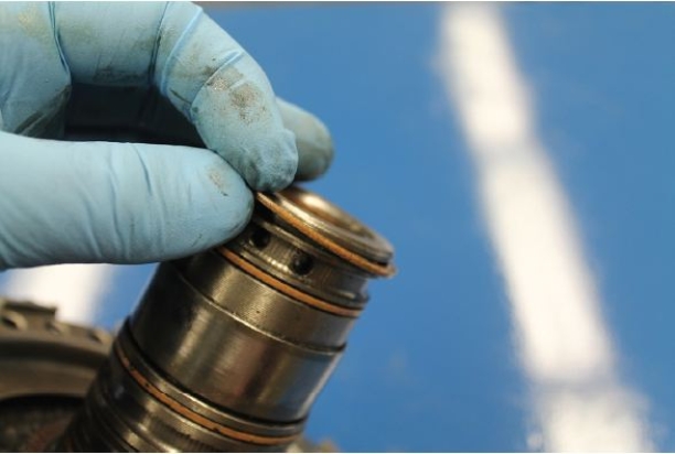 Identify the component that is being removed in the given figure.   A)  Sealing ring B)  Front pump bushing C)  Accumulator spring D)  Alignment band