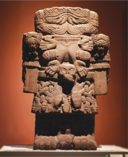   How does the Aztec sculpture of Coatlicue (figure 17.17)  from the central pyramid complex of Tenochtitlán embody her formidable and intimidating nature? A)  Snakes for blood, armor, and wood material B)  Abstraction, clawed fingers, and Storm God imagery C)  Human skulls, compact mass, and a beard D)  Large size, compact mass, and imagery of violence