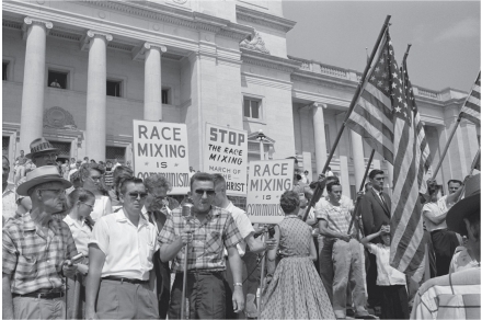   -This image of a protest against desegregation at Little Rock's Central High School shows A)  The violence inherent in segregationist protests B)  The role of fears of miscegenation in segregationist rhetoric C)  The linking of racist and anticommunist rhetoric D)  All of the above
