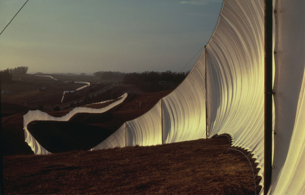 ​   Which feature describes Christo and Jeanne-Claude's Running Fence ? A) This work permanently transformed its setting through its balance of light and shade. B) It was constructed of cloth stretched across miles of California countryside. C) It was a departure for the artists, who mostly created kinetic sculptures. D) As an assemblage, we see the way it incorporates found objects into an artwork.