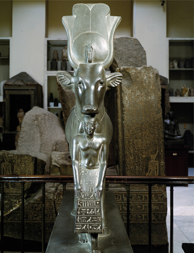 ​   Which element can be seen in the statue The Goddess Hathor and the Overseer of Sealers, Psmatik ? A) The inspiration from early reed architecture in its decorative patterns B) Lotus bud capitals C) Successively darker, smaller spaces D) The Egyptian use of animal forms to depict deities