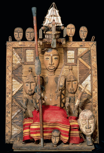 ​   What is the significance of the headdress worn by the central figure in this Kalabari ancestral screen? A)  Reference to the travels of the deceased around the coasts of Africa B)  Reference to the deceased chief's successful trading business C)  Reference to the ravages of the slave trade on the family of the deceased D)  Reference to the god of the equatorial trade winds