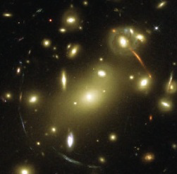    The multiple images forming a ring around the cluster come from two merging distant galaxies.